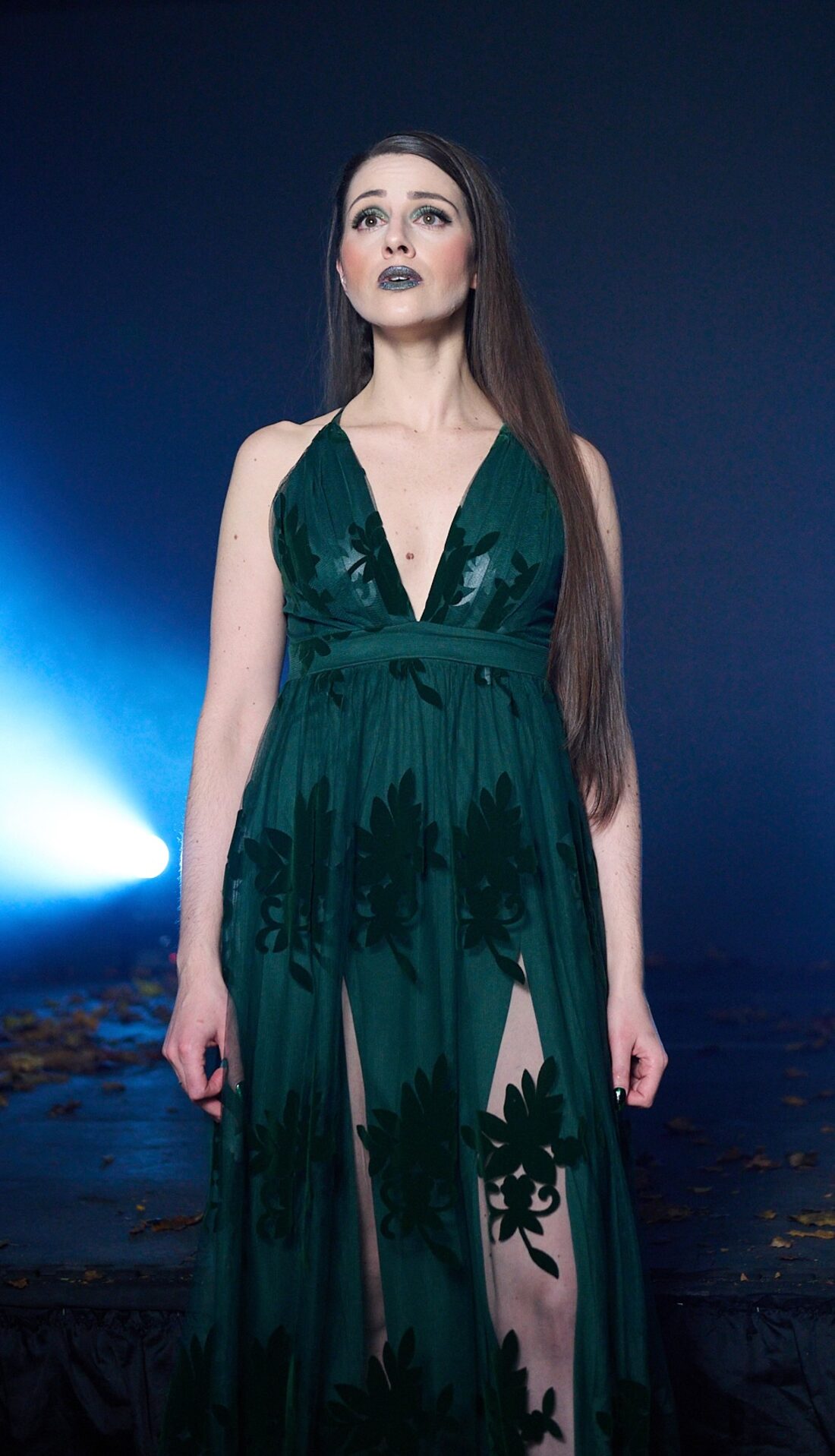 Regina Bianca on stage in a flowing gown, lit by a single blue spotlight