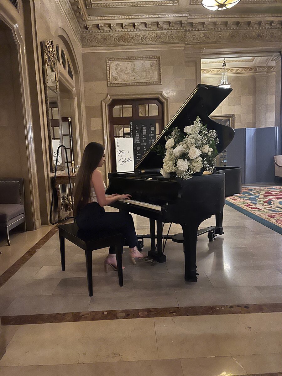 A grand piano set with white florals in an elegant ceremony hall