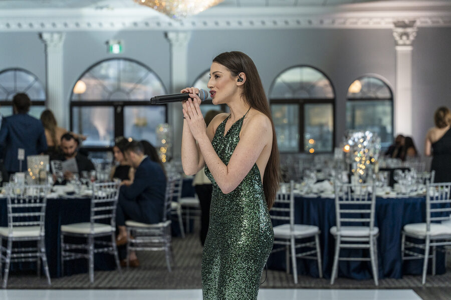 Regina Bianca performing in a candlelit ballroom as guests gather